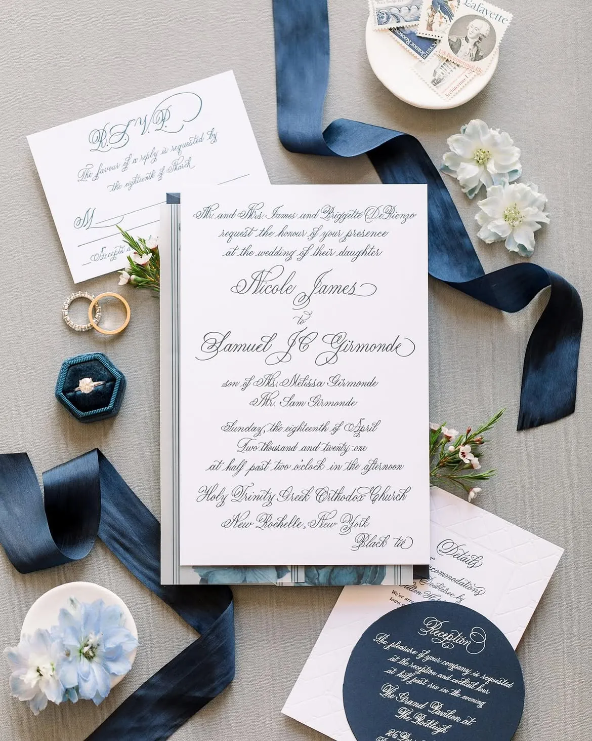 Formal calligraphy invitation with a navy silk ribbon, round navy reply card, and wedding rings